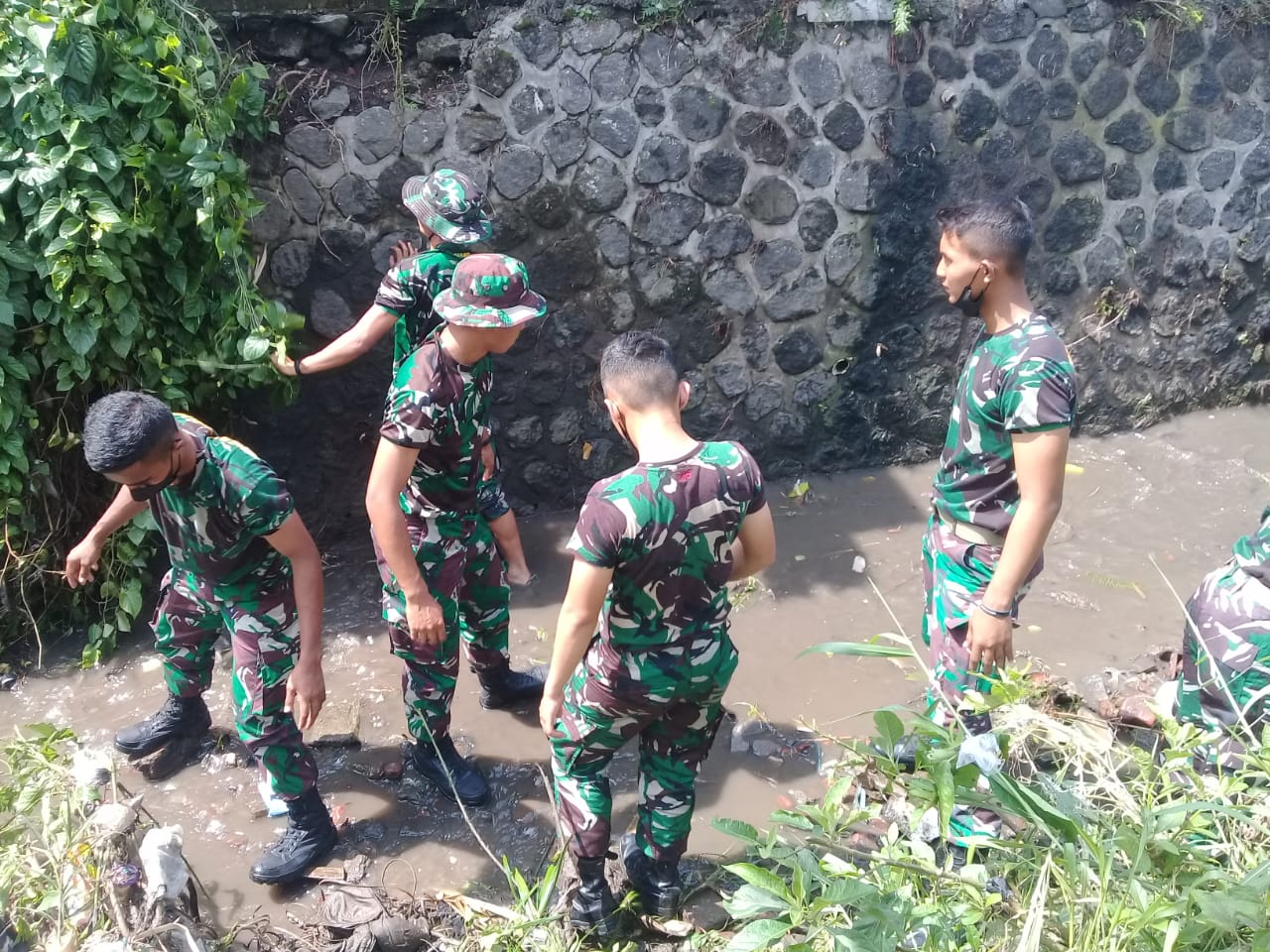Anggota TNI membersihkan rumput yang tumbuh di sekitaran sungai. Foto: Ist